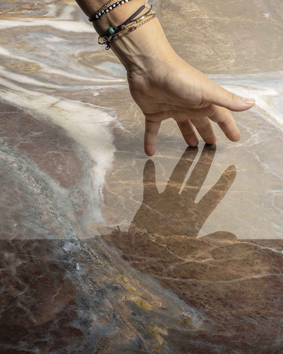 Architect's hand exploring a polished marble slab — Divya Stones contact